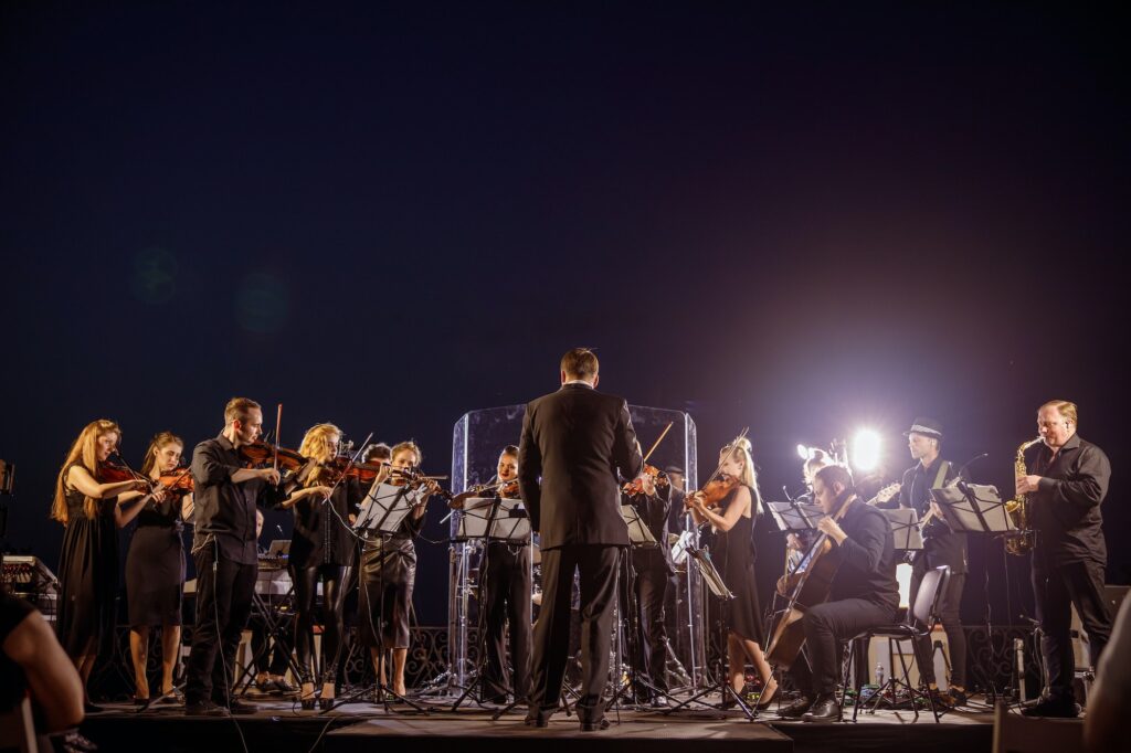 An orchestra performing at night that a student might listen to at an expert level.